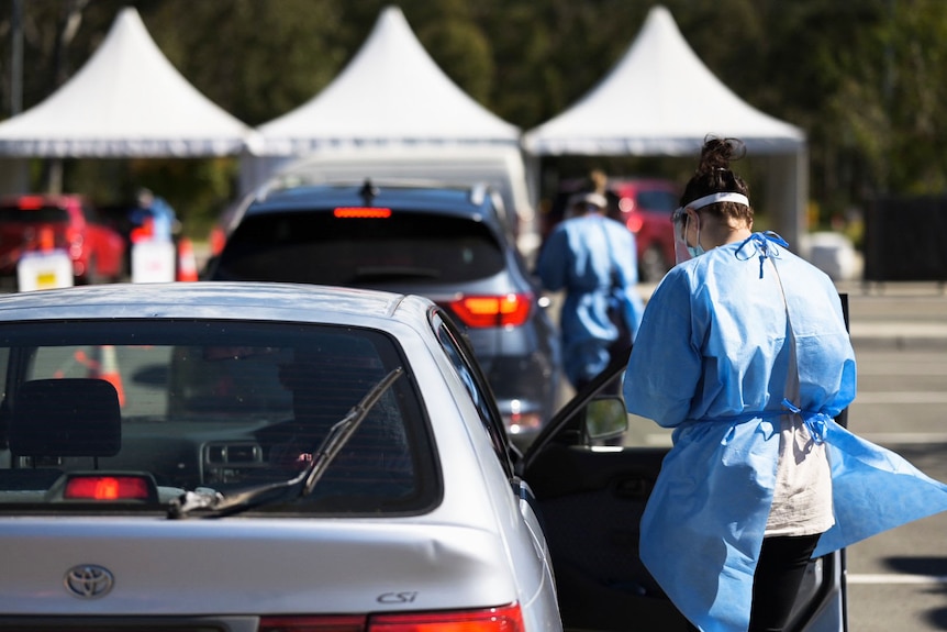 Health workers and cars at a drive-through COVID-19 testing clinic in Brisbane
