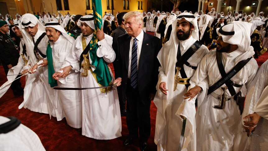 Donald Trump holds a sword and sways with traditional dancers during a welcome ceremony at Murabba Palace