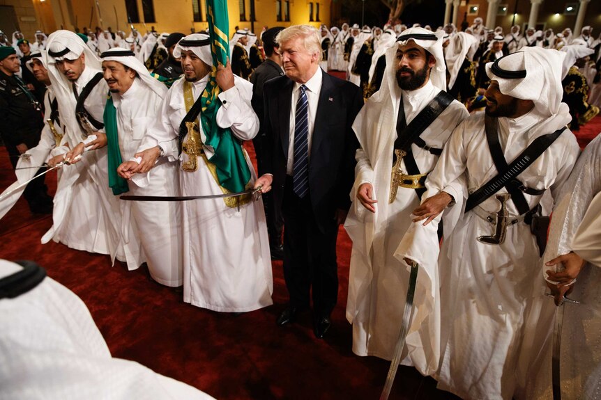 Donald Trump holds a sword and sways with traditional dancers during a welcome ceremony at Murabba Palace