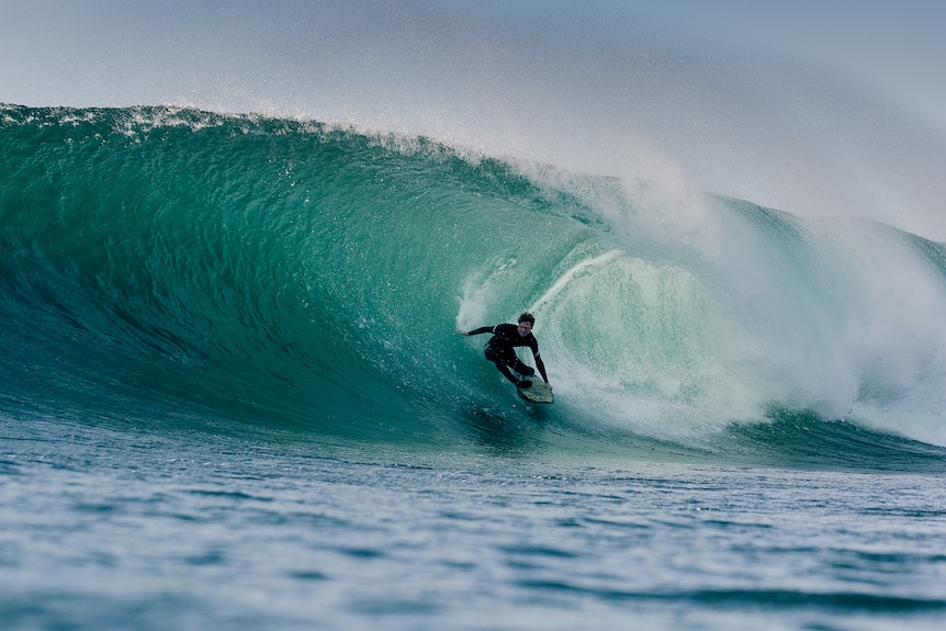A surfer rides a large wave.