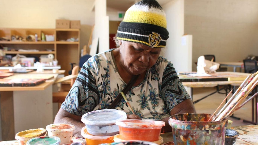 Artist Nyinta Donald looks down while painting at the Tanentyere Artists workshop in Alice Springs
