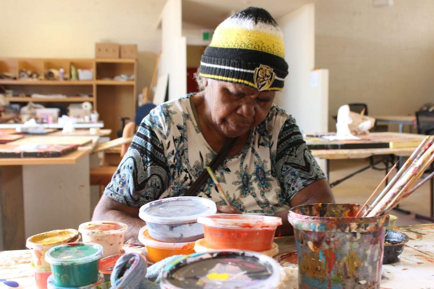 Artist Nyinta Donald looks down while painting at the Tanentyere Artists workshop in Alice Springs
