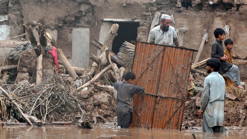 Local residents remove a gate from their damaged house in a flood-hit area of Nowshera