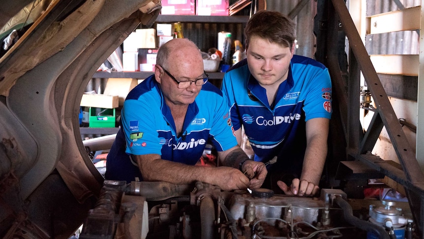 Cameron Rowland works on a car with his father in a workshop