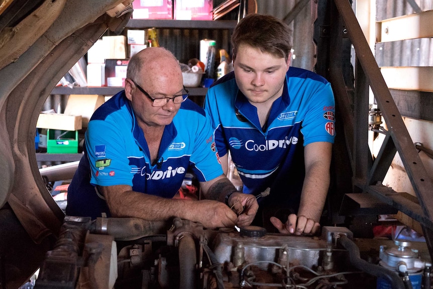 Cameron Rowland works on a car with his father in a workshop