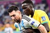 Argentina's Lionel Messi shields the ball from Socceroos player Garang Kuol at the World Cup in Qatar.