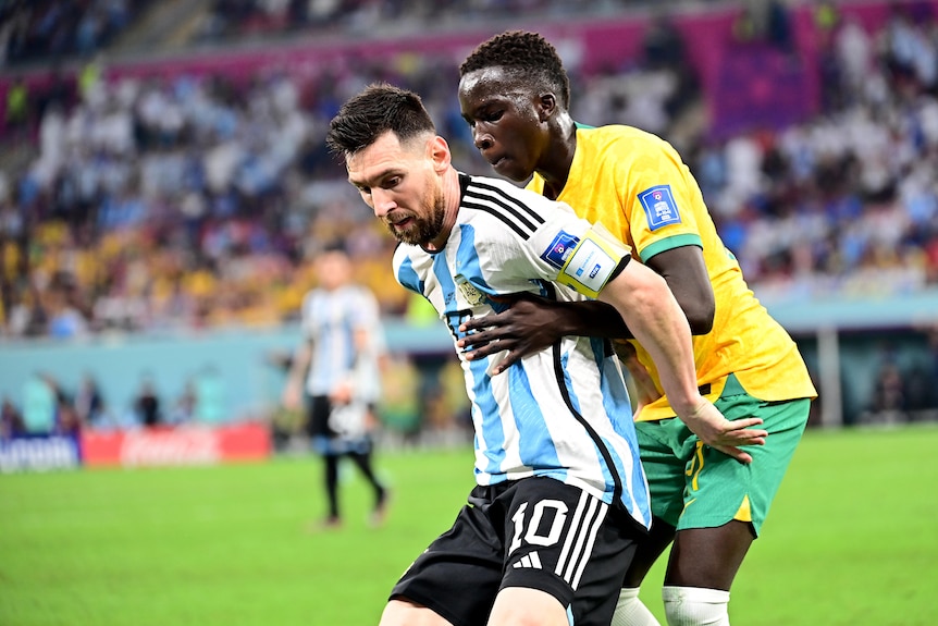 Lionel Messi de Argentina protege el balón del jugador de los Socceroos Garang Kuol en la Copa del Mundo en Qatar.
