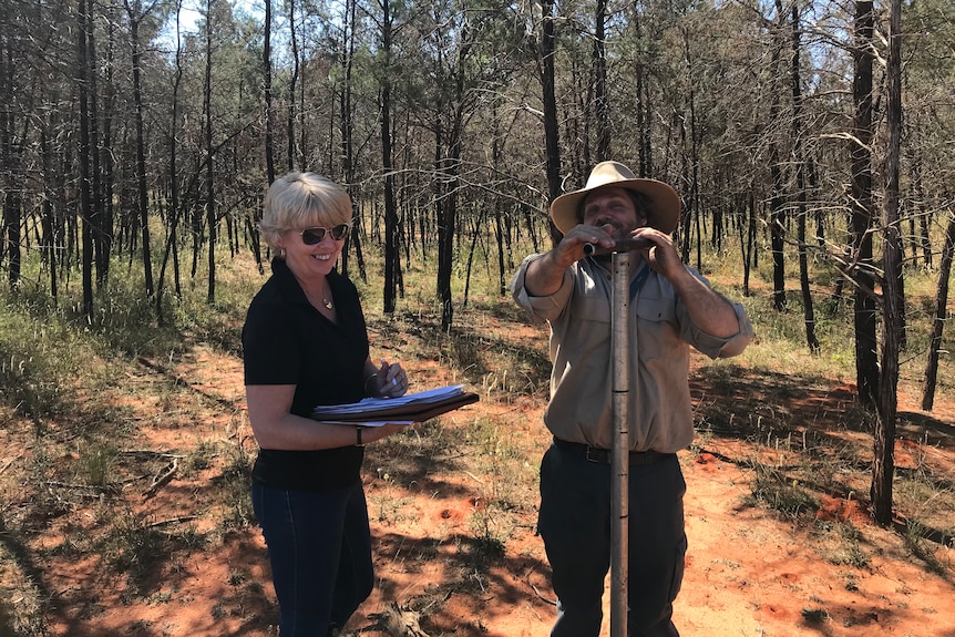 Leanne Brosnan and Dave Harper standing together smiling while conducting field work. 