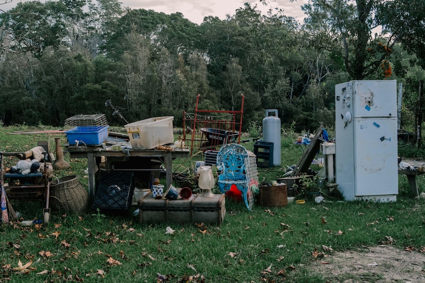 A pile of household items including a fridge, chairs and baskets on the lawn.