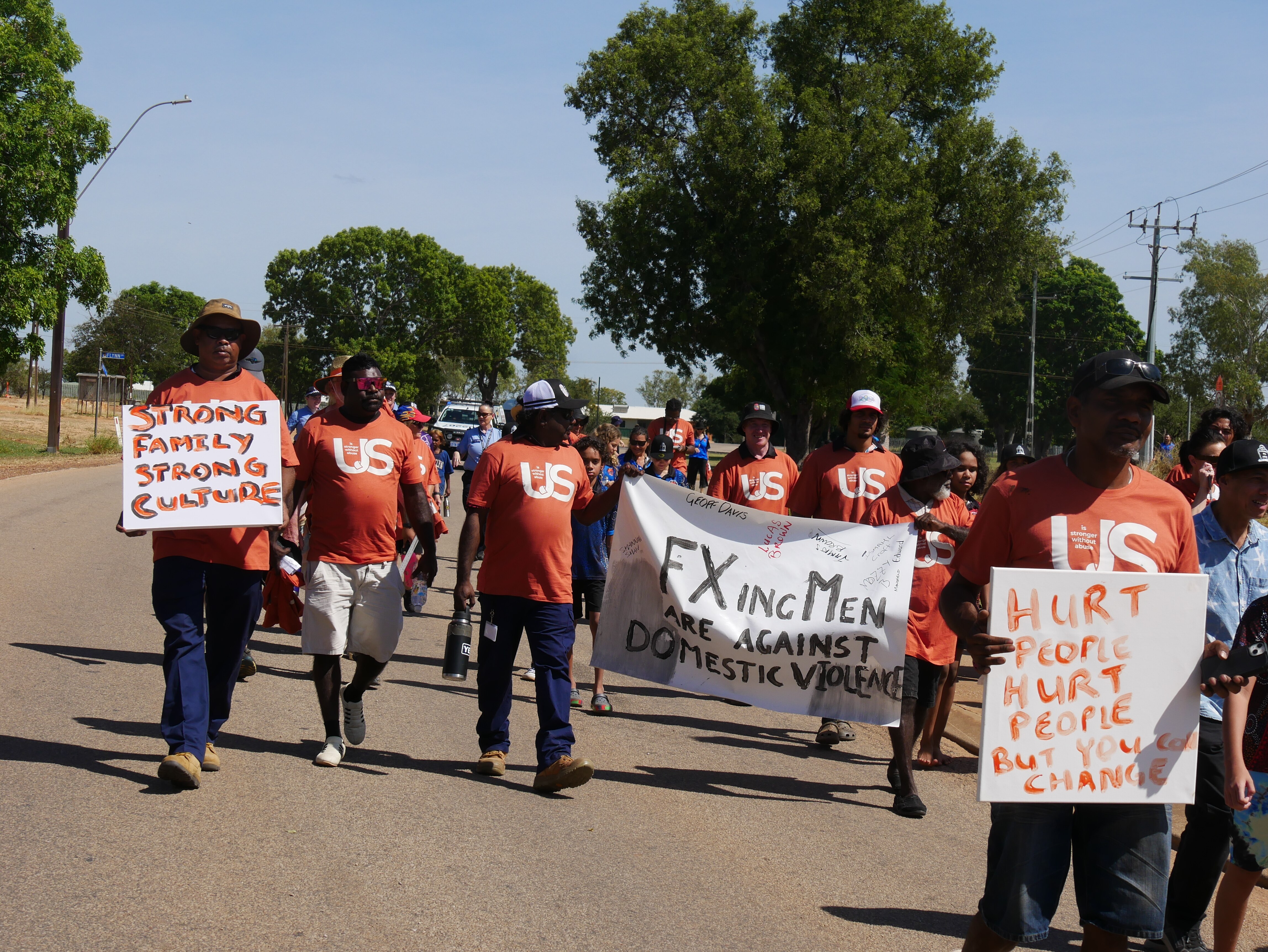 A group of people walk on a street with banners