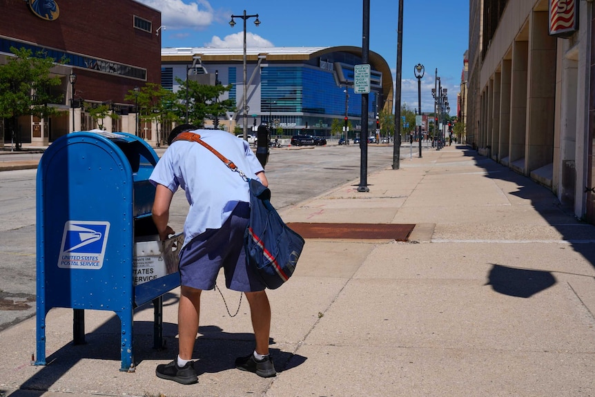 A US postal worker empties a post box.