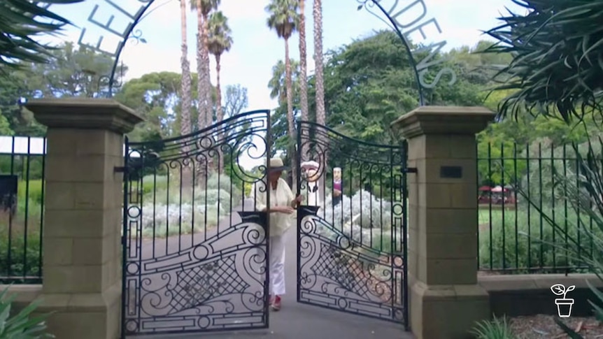 Woman opening gates with 'Geelong Botanic Gardens' written in the arch