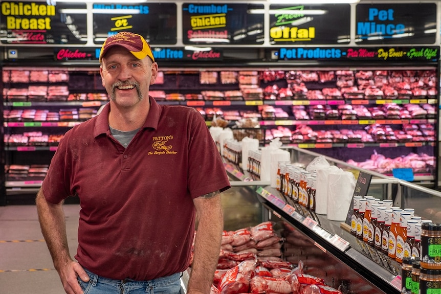 A butcher standing in his shop with meat all around