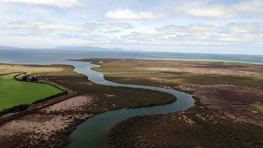 Aerial image of Corner Inlet with speckled cloud in the sky and mountains on the horizon.