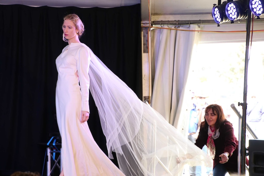Eco Fashion Week Australia founder Zuhal Kuvan-Mills helping a model with wedding dress train.