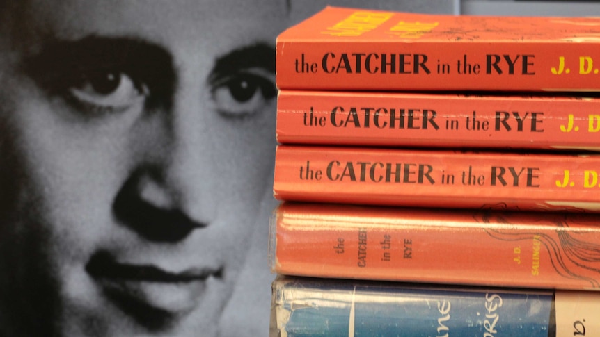 A stack of J.D. Salinger's classic novel "The Catcher in the Rye" stands next to an image of the author.