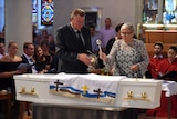 Steven and Mary-Leigh sprinkle holy water on the coffin of their son, Cole Miller.