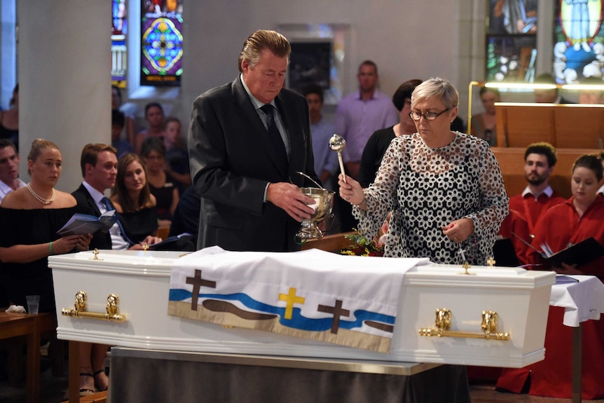 Steven and Mary-Leigh sprinkle holy water on the coffin of their son, Cole Miller.