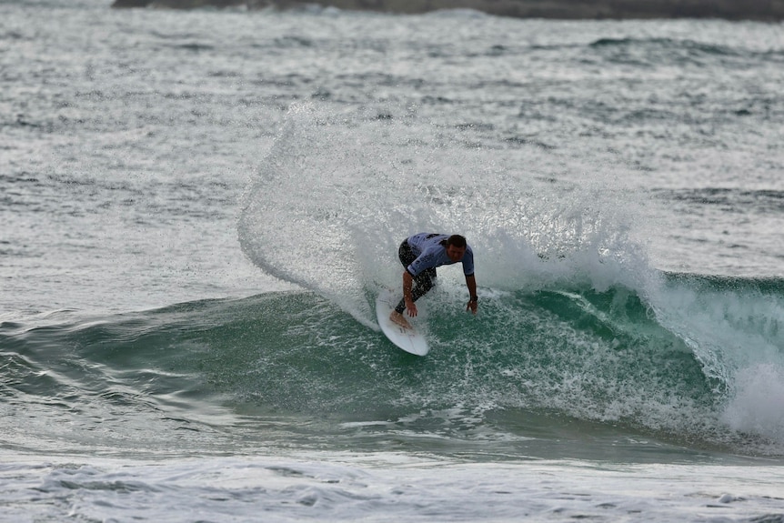 A man over 35 surfing a wave doing a cutback.