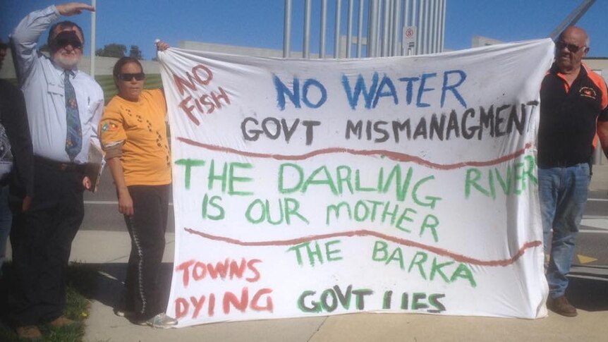 Water campaigners stand with hand-made sign