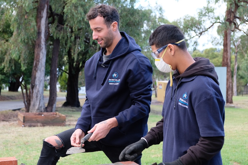 Daniel Ricciardo with a trowel in his hand.