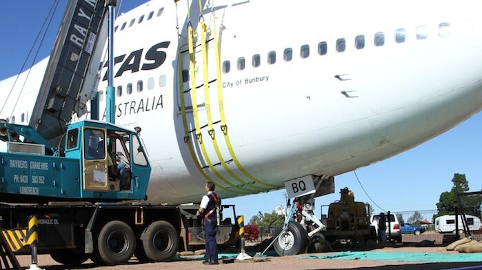 Crane supports jumbo jet sinking into the ground at a display at the Qantas Founders Museum in Longreach.