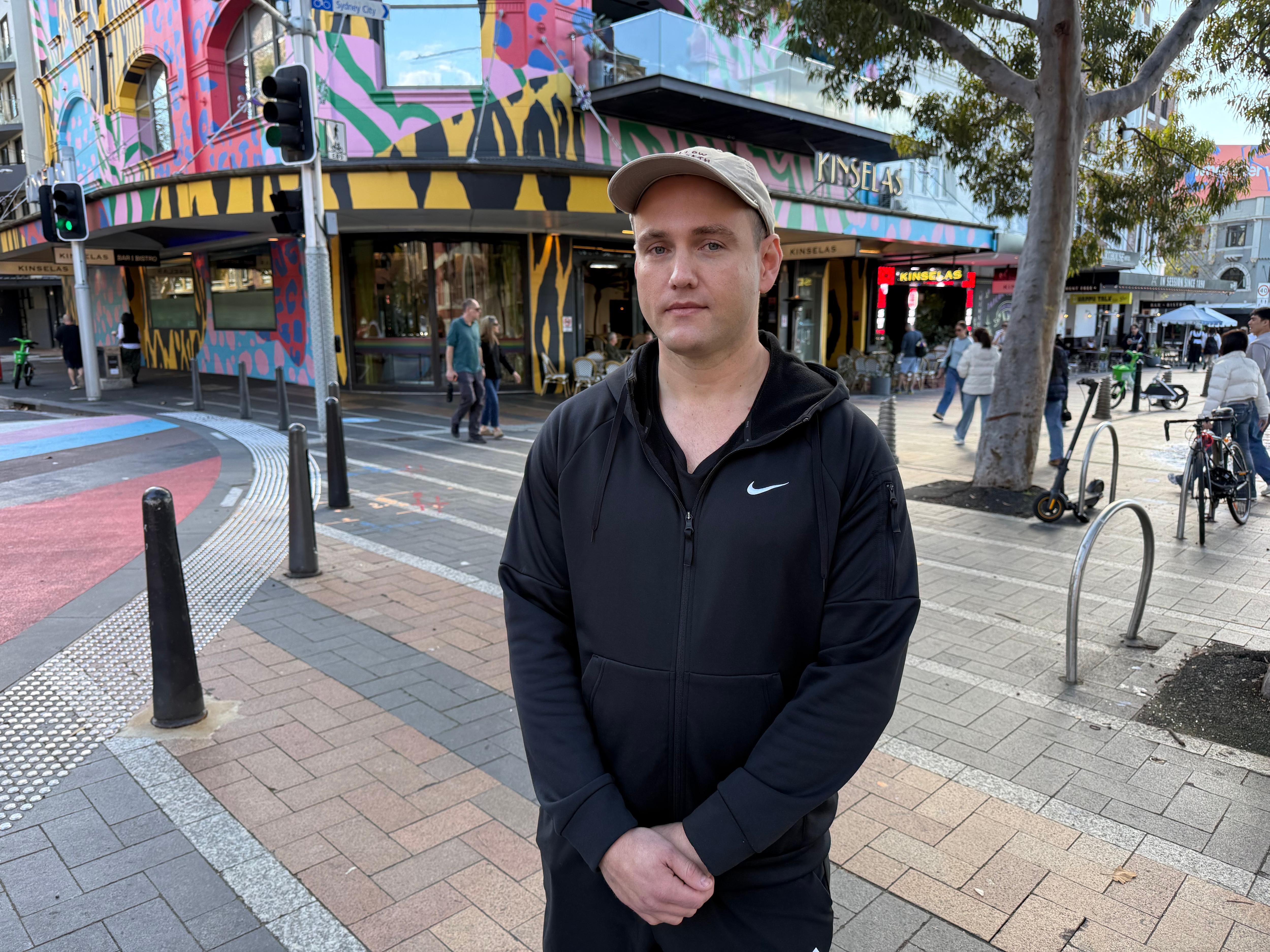 Kristoffer stands on oxford street wearing a cap looking at the camera