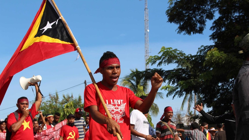 A protester holds an East Timor flag as he marches with several thousand other protesters.