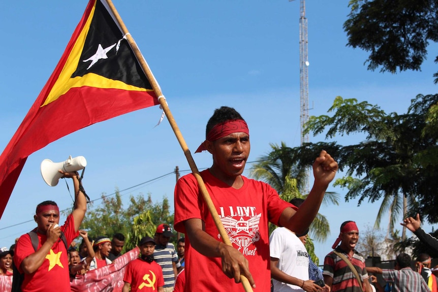 A protester holds an East Timor flag as he marches with several thousand other protesters.