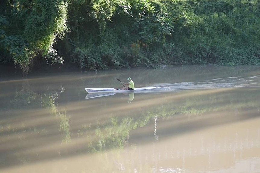 A man canoes in brown water in the river.
