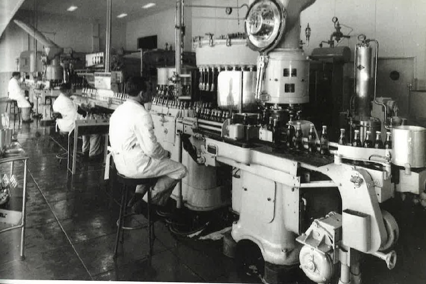 an old black and white photo of a factory with cola bottles