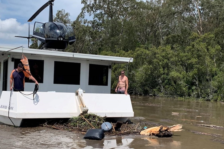 a helicopter atop a houseboat on a river