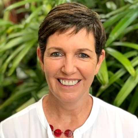 Woman smiling in front of green foliage