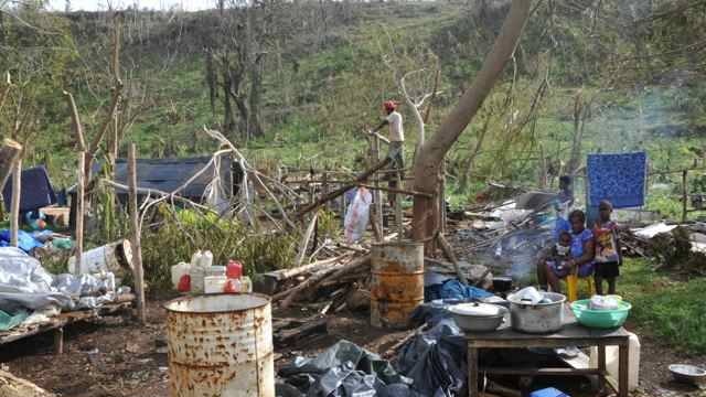 Family sits by fire among ruins of home and garden after Cyclone Pam in Vanuatu