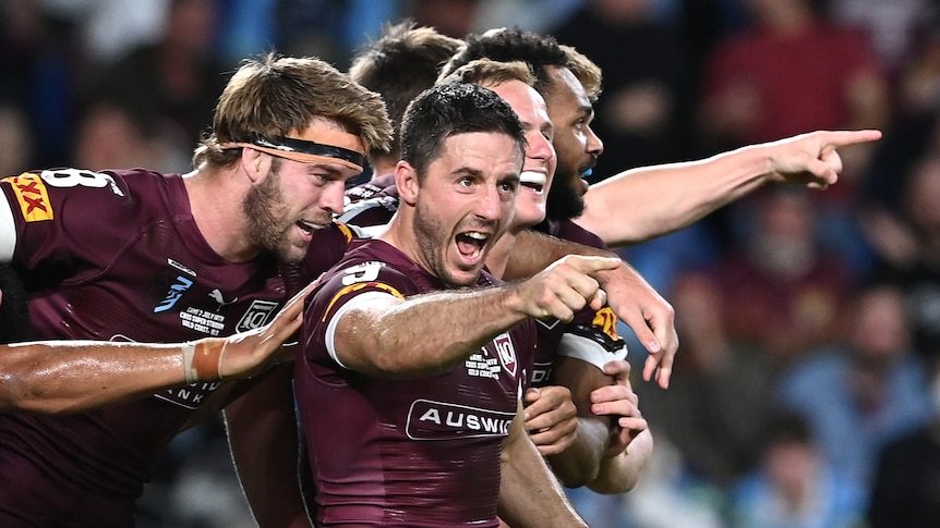 Ben Hunt points and shouts as his Queensland Maroons teammates celebrate with him during a State of Origin game.