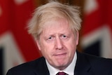 Boris Johnson with pursed lips and worried eyes speaks at a podium.