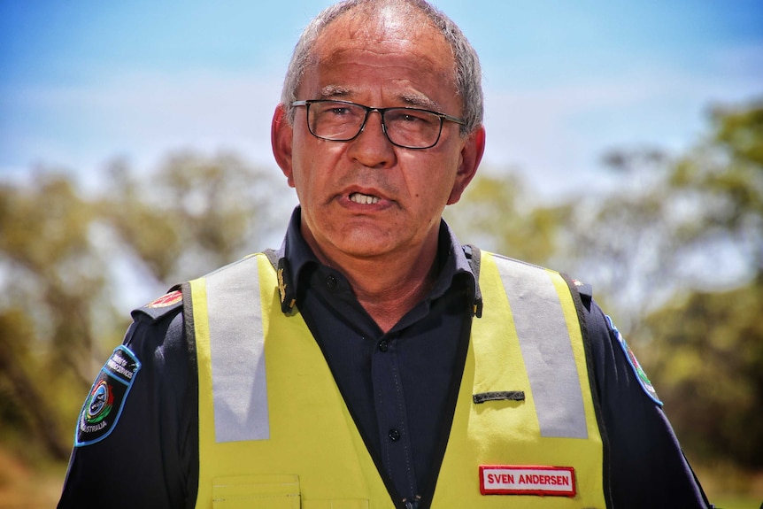 A man in a firefighter's uniform stands outdoors, addressing the media.