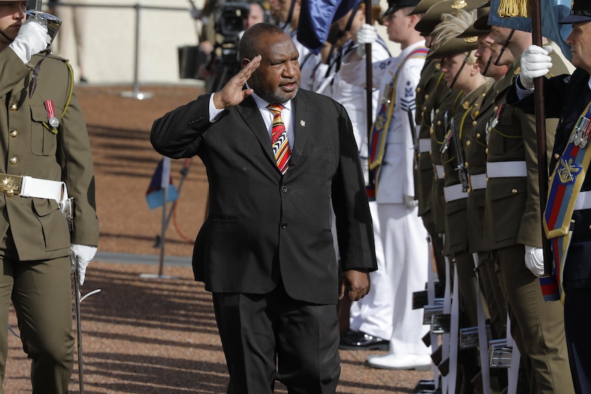 James Marape salutes as he walks past defence personnel outside parliament house.