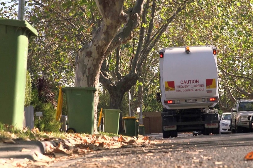 A recycling truck drives down a suburban street