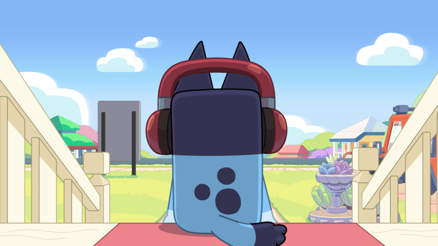 Bluey wearing headphones, sits on his front door step with her back to the camer.
