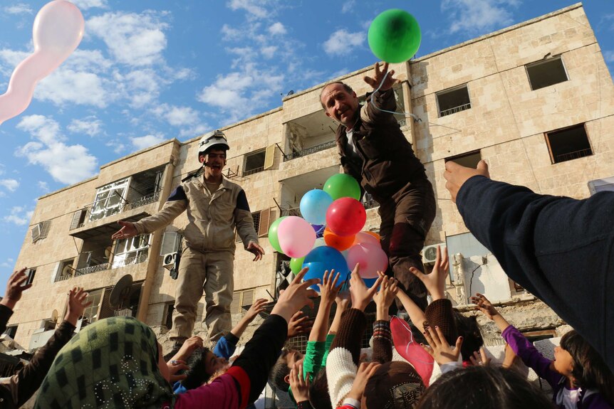 Man hands out coloured balloons in the Syrian city of Aleppo