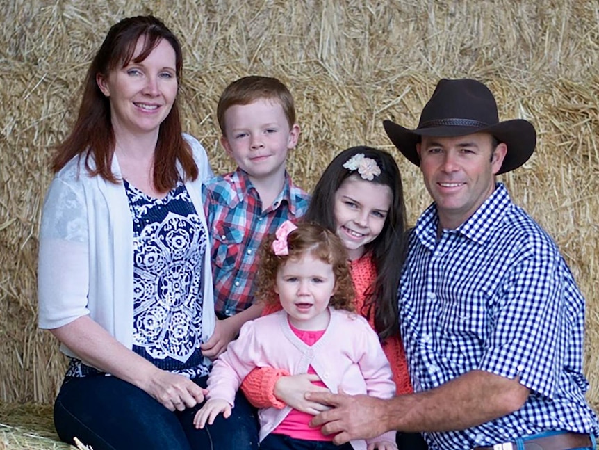 Family portrait of Michael and Ancret Shipton with their three small children sitting on hay bales.