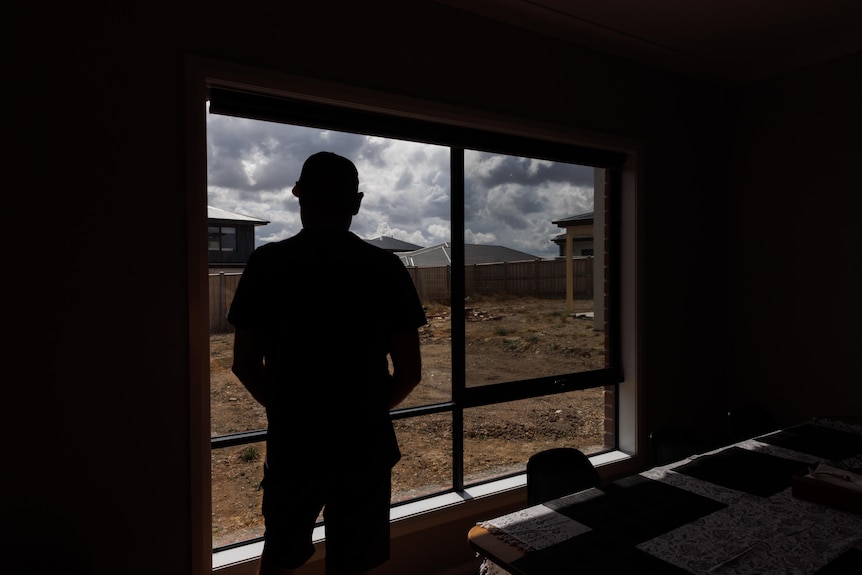 A silhouette of a man staring out a window.