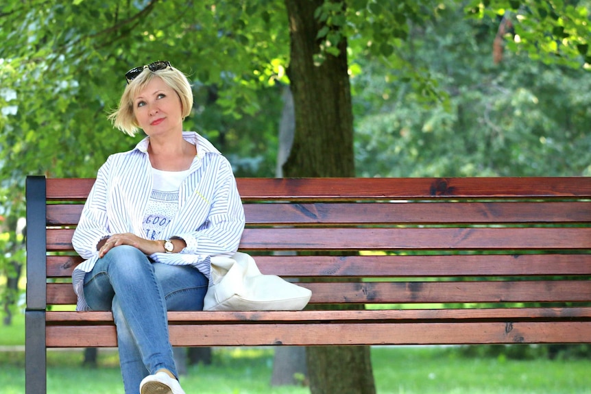 A woman sits thinking on a bench.
