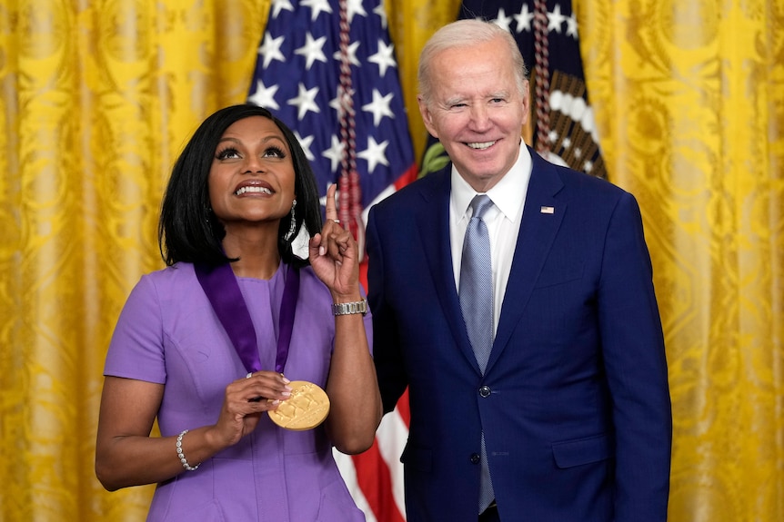 Mindy Kaling poses with a medal next to Joe Biden