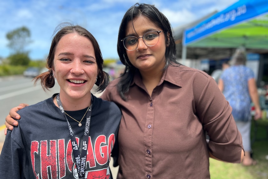 Two young women in front of market stall