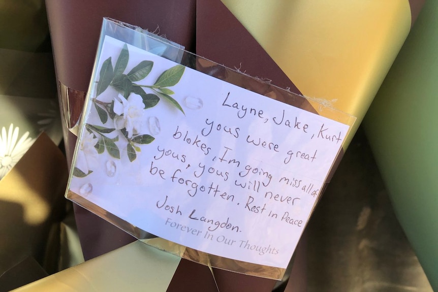 A tribute message left on a bouquet of flowers.