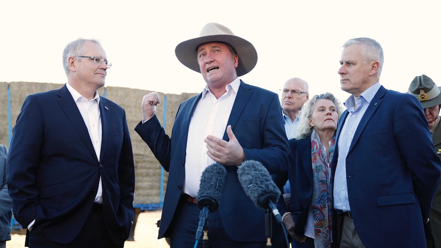 Barnaby Joyce speaks at a press conference with Scott Morrison and Michael McCormack in front of a hay truck