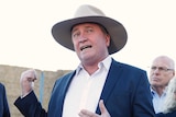 Barnaby Joyce speaks at a press conference with Scott Morrison and Michael McCormack in front of a hay truck