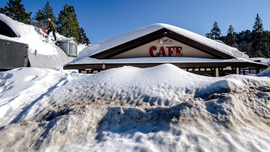 A cafe is pictured with a big mountain of snow in front of it.